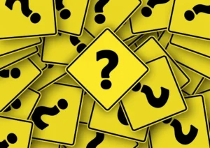 A pile of yellow road signs with black question marks, symbolizing confusion or uncertainty.